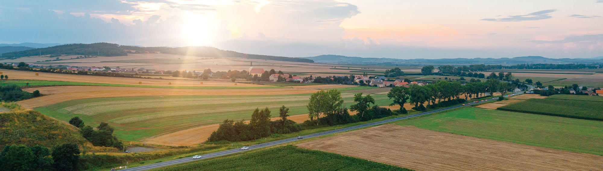 A beautiful sunrise lighting up the sky over some pastures and farmland.