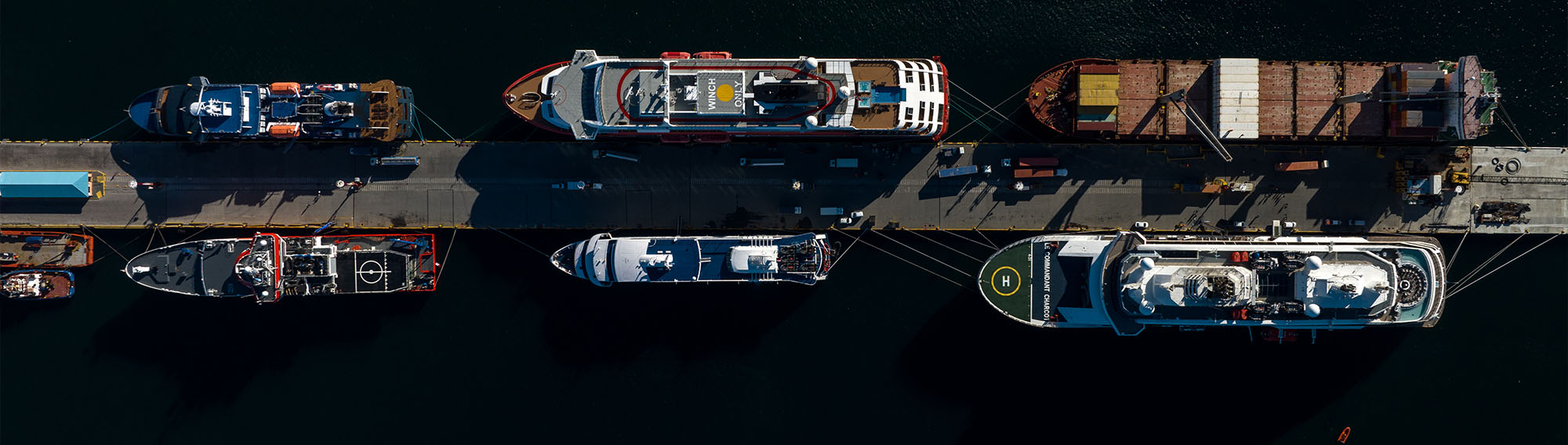 Aerial top view of multiple cargo ships at a port.